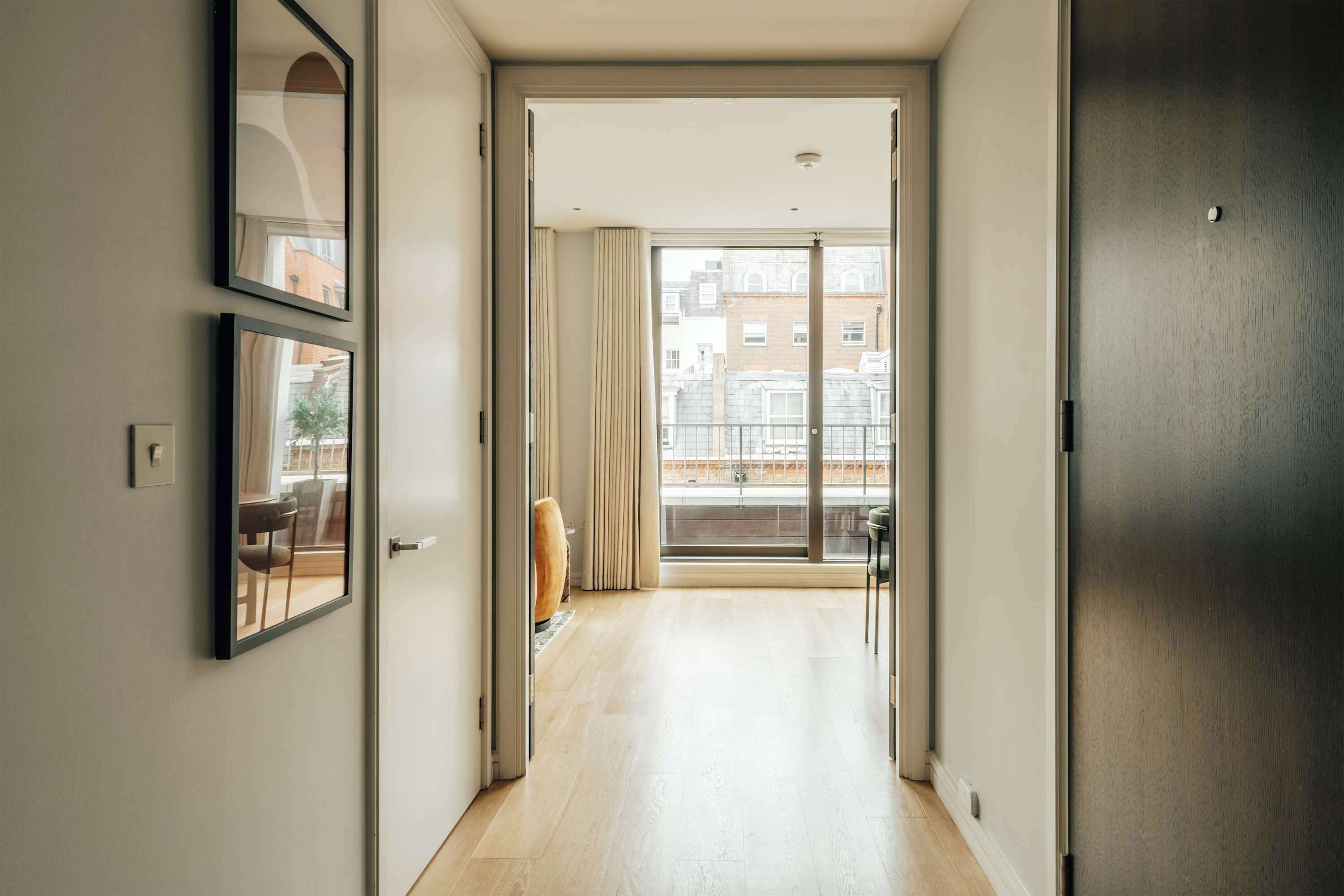 A hallway leading to a balcony with a view of buildings.