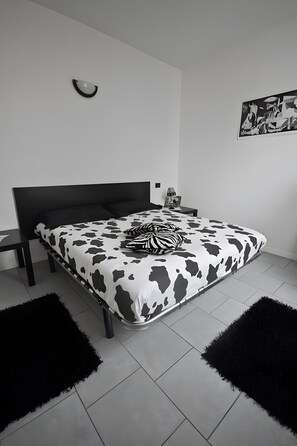 A modern bedroom with a black and white cow print bedspread, a black headboard, and a minimalist design. - Bed and Breakfast 'Suite Onorio Lago Di Como' with Shared Pool, Shared Garden and Wi-Fi (Pontaccio)