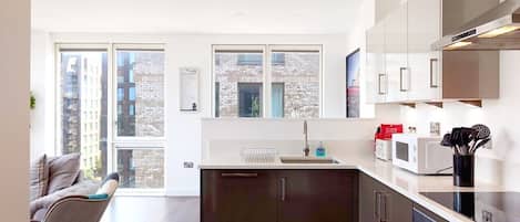 A modern kitchen with a central island, built-in appliances, and large windows offering views of the city.