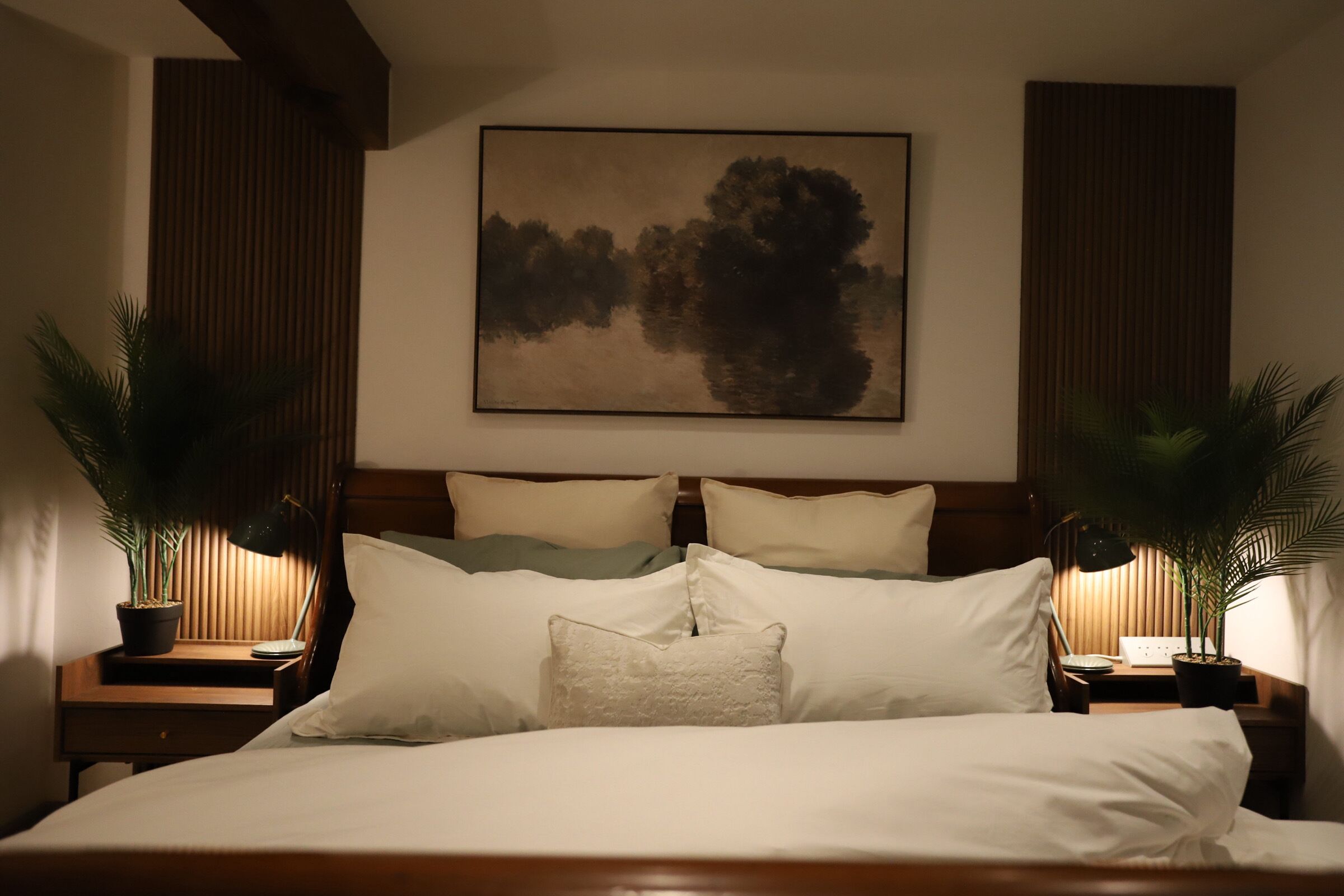Une chambre à coucher avec un grand lit, deux tables de chevet avec des lampes et un tableau au mur.