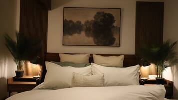 Une chambre à coucher avec un grand lit, deux tables de chevet avec des lampes et un tableau au mur.