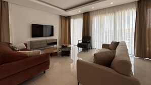 Een moderne woonkamer met een flatscreen televisie, een bank, een fauteuil en een salontafel.