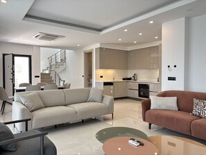 A modern living room with a sofa, a coffee table, and a dining area with chairs. - Elegant 5BR Villa | Private Pool (Bodrum)