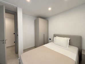 Ein Schlafzimmer mit einem Bett, einem Kleiderschrank und einer Tür zu einem anderen Raum.