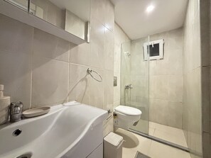 Ein modernes Badezimmer mit Waschbecken, Toilette und einer Duschkabine aus Glas.
