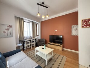 A living room with a sofa, coffee table, TV, and a dining area with chairs and a table. - Comfortable 2BR | Walk to Sultanahmet (Istanbul)