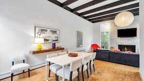 Una sala de estar moderna con chimenea, muebles blancos y un televisor montado en la pared.