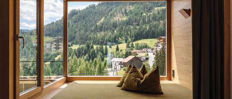 A room with a large window offering a view of a forested hillside.