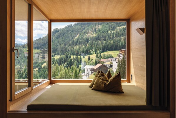 Una habitación con un amplio ventanal que ofrece vistas a una ladera boscosa.