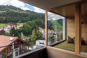 Een kamer met een groot raam dat uitkijkt over een bergachtig landschap met gebouwen en een brug.