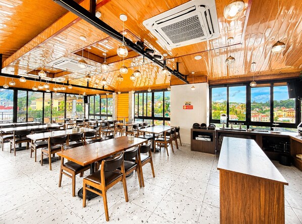 A spacious restaurant with high ceilings, wooden beams, and large windows offering a view of the cityscape. - Palette H&T Centre Sapa Hotel (Sa Pa)