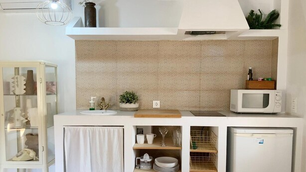 A compact kitchen with a white countertop, a microwave, a refrigerator, and a small sink.