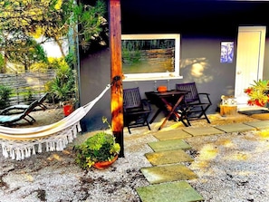 A patio with a hammock, outdoor seating, and a window overlooking a garden. - Quinta do Meco - Beach & Nature (Sesimbra)
