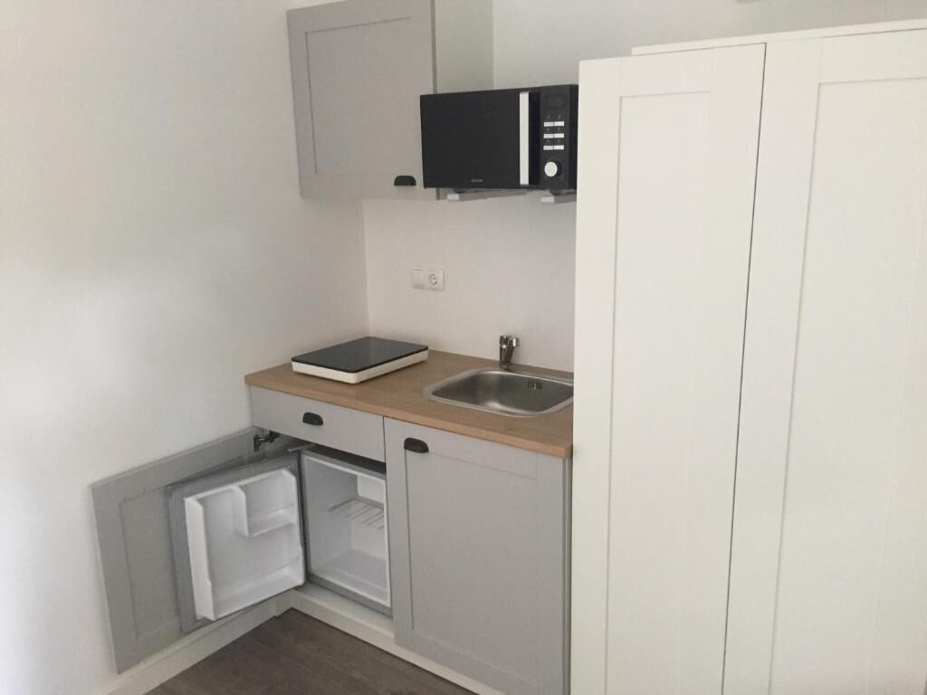 Eine kompakte Küche mit einer Mikrowelle, einem Spülbecken und einem kleinen Kühlschrank.