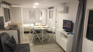 Un espacio habitable compacto con kitchenette, comedor y televisor.