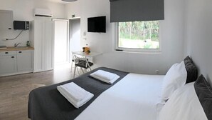 Un dormitorio con cama, escritorio y ventana.
