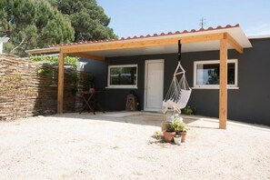 A covered outdoor area with a wooden pergola, a hanging chair, and potted plants. - Quinta do Meco - Beach & Nature (Sesimbra)