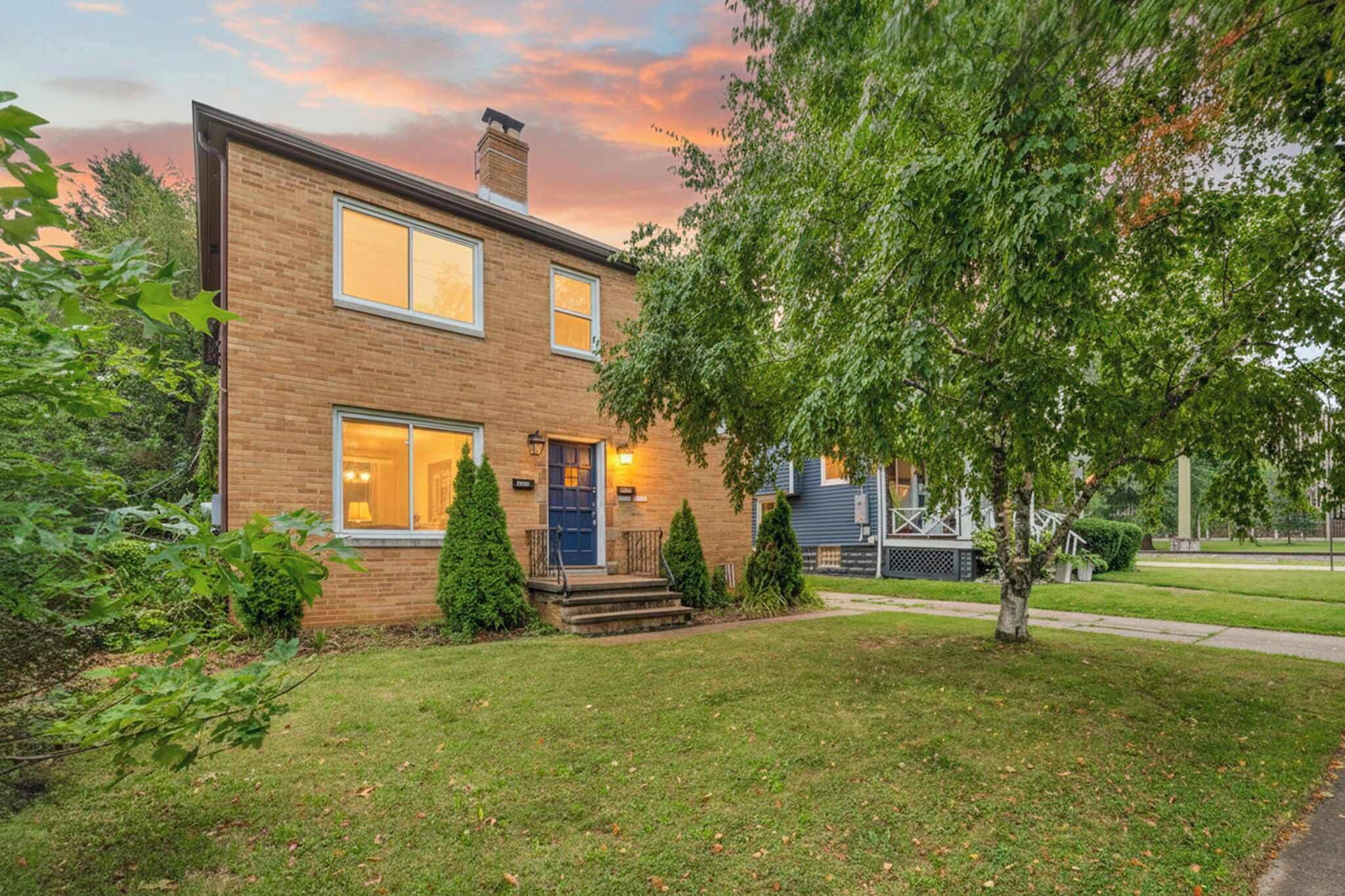 A two-story brick house with a front porch, a mailbox, and a well-maintained lawn.