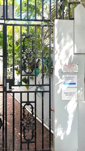 A gated entrance with a security sign, a keypad, and a gate marked with apartment numbers. - Beach, Cafés & La Placita on Foot / Condado (San Juan)