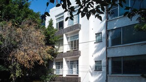 A white building with a blue door, multiple windows, and a visible address sign. - Confortable 2 Bedroom accomodation C3 (Ciudad de México)