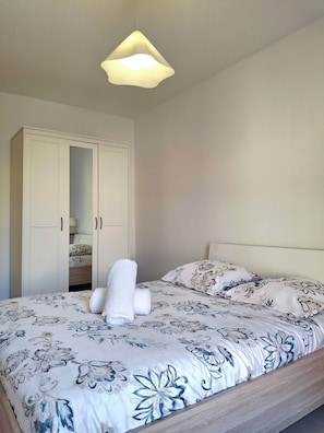 Une chambre à coucher avec un lit, une armoire et un luminaire suspendu.
