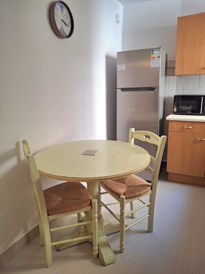 Une petite cuisine avec une table ronde, des chaises, un réfrigérateur et un four à micro-ondes.