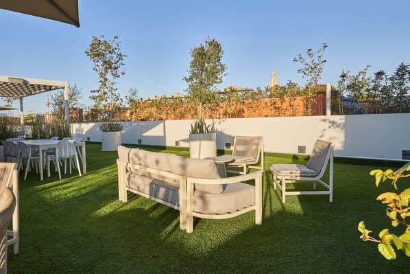 Eine Terrasse mit einer Couch, Stühlen und einem Esstisch.