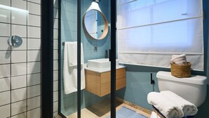 A modern bathroom with a glass shower enclosure, a white sink, and a toilet with a basket of towels. - Nice room with private bathroom La Condesa C16 (Ciudad de México)