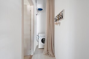 A laundry room with a washing machine, a drying rack, and a shower head on the wall. - Holiday Home 'Trulli Marosa' with Private Pool, Wi-Fi and Air Conditioning (Castellana Grotte)