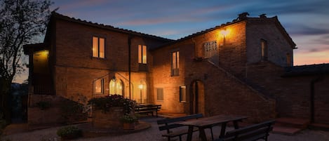 A brick house with a patio, outdoor seating, and a well-lit entrance.