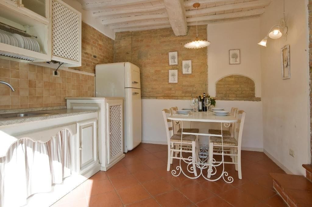 A kitchen with a white refrigerator, a dining table with chairs, and a tiled backsplash.