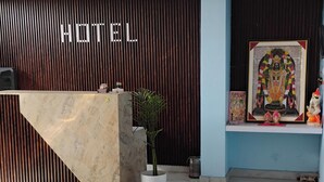 En hotellobby med en marmordisk, en krukväxt och en inramad religiös bild utställd.