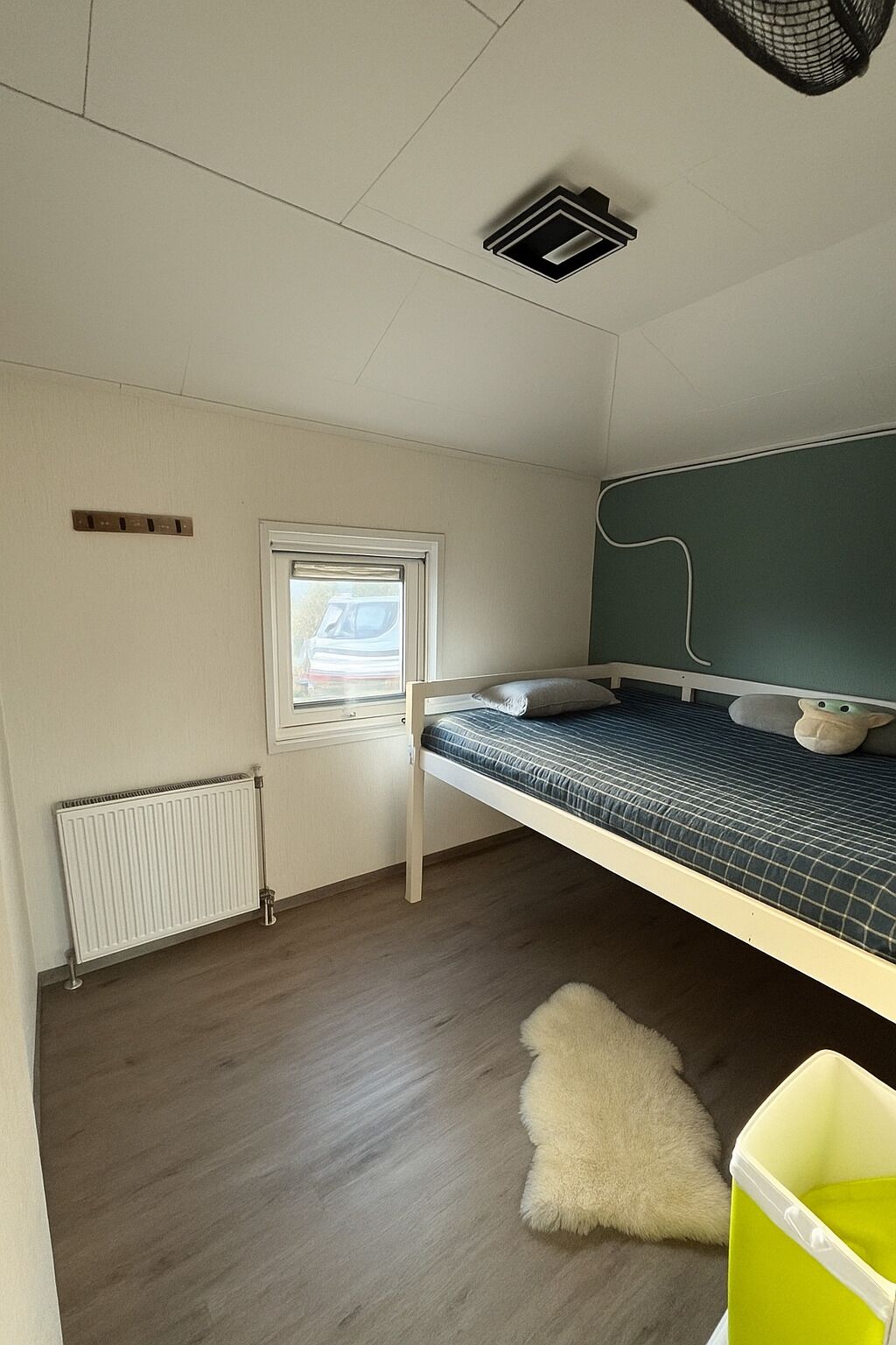 A bunk bed room with a window, radiator, and a small furry rug.