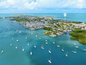 An aerial view of a coastal area with numerous sailboats docked in calm waters, surrounded by a densely populated urban area with buildings and greenery. - *NEW* Reel Escape~50'Dock!!~Pet Friendly!~Grill! (Marathon)