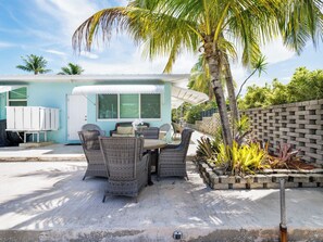 A patio with wicker furniture, a small building with a white awning, and a palm tree. - *NEW* Reel Escape~50'Dock!!~Pet Friendly!~Grill! (Marathon)