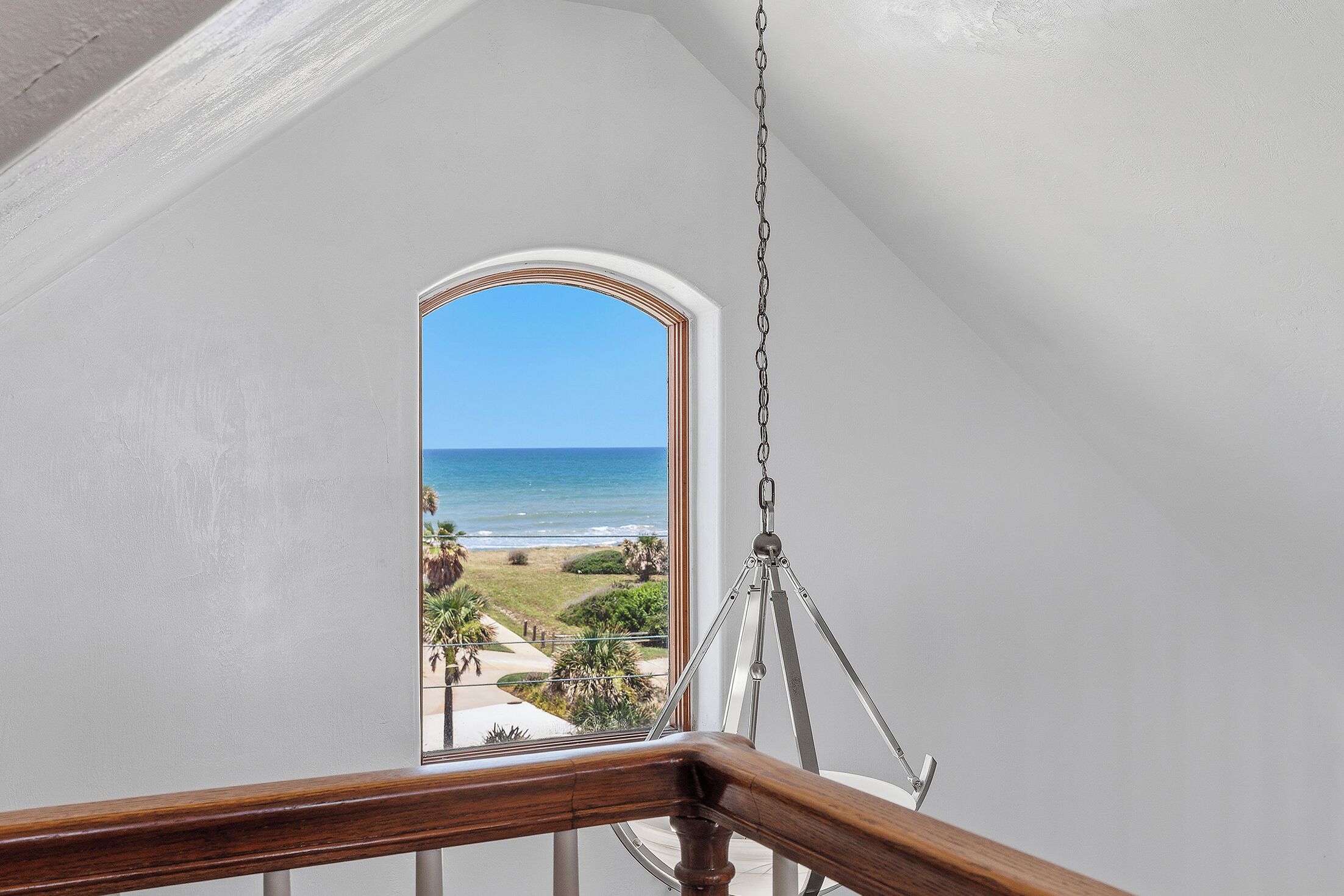 A staircase with a view of the ocean through a window.