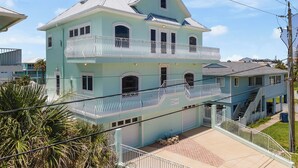 Uma casa de dois andares com varanda, garagem e escada que leva ao andar superior.