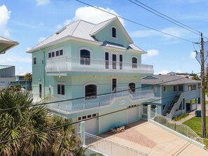 Ein zweigeschossiges Haus mit Balkon, Garage und einer Treppe, die zu den oberen Stockwerken führt.