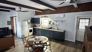 Une cuisine moderne avec un coin repas, un plancher en bois et des ventilateurs de plafond.