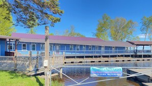 Une propriété située au bord de l’eau, dotée d’un quai, d’un espace abrité et d’un bâtiment dont le toit est de couleur violette.