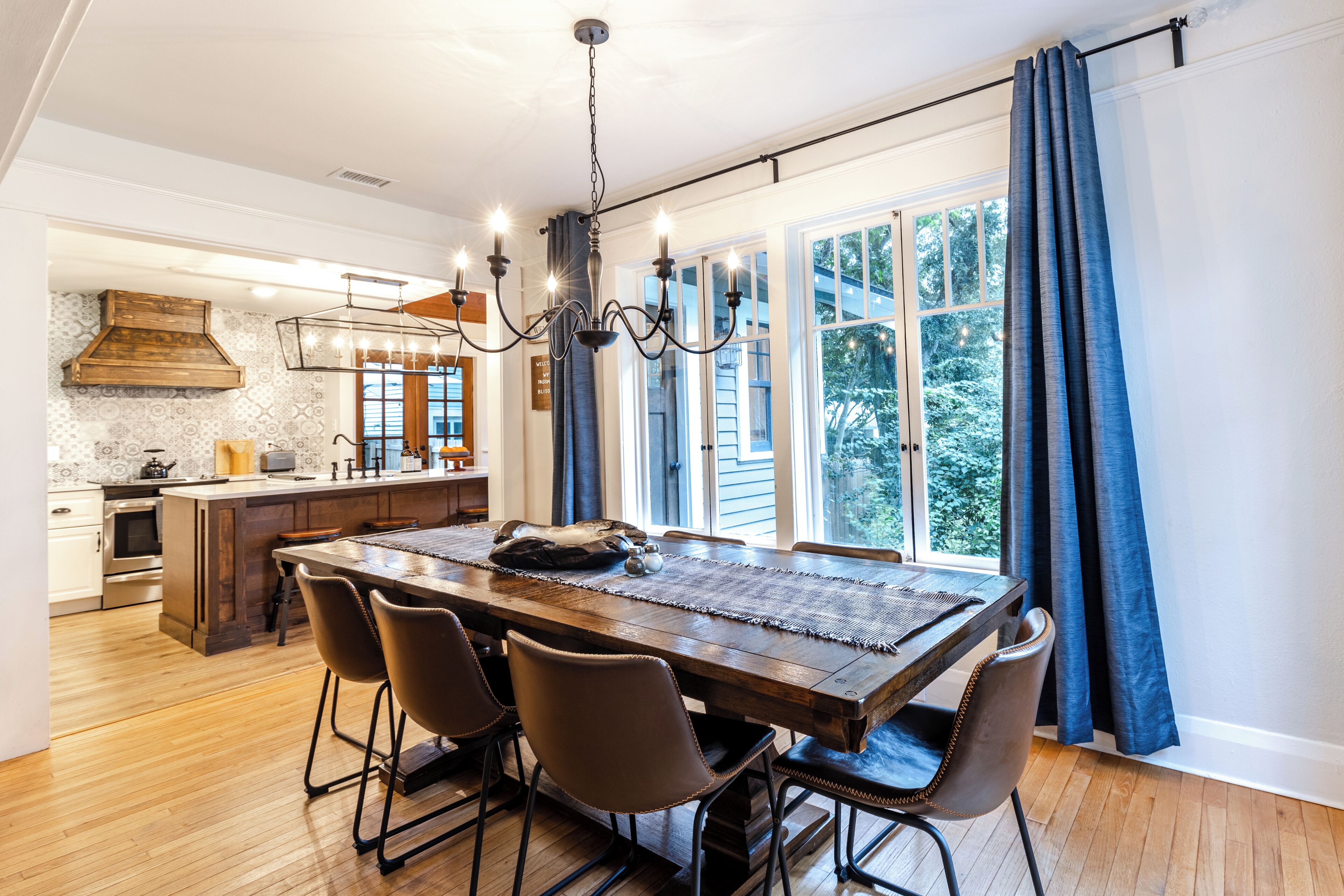 Un coin repas avec une table en bois, quatre chaises et un lustre.