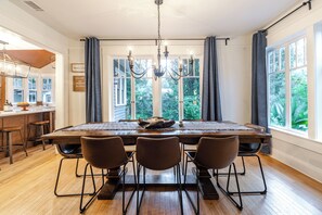 Ein Esszimmer mit einem großen Holztisch, vier Stühlen und einer Deckenleuchte.
