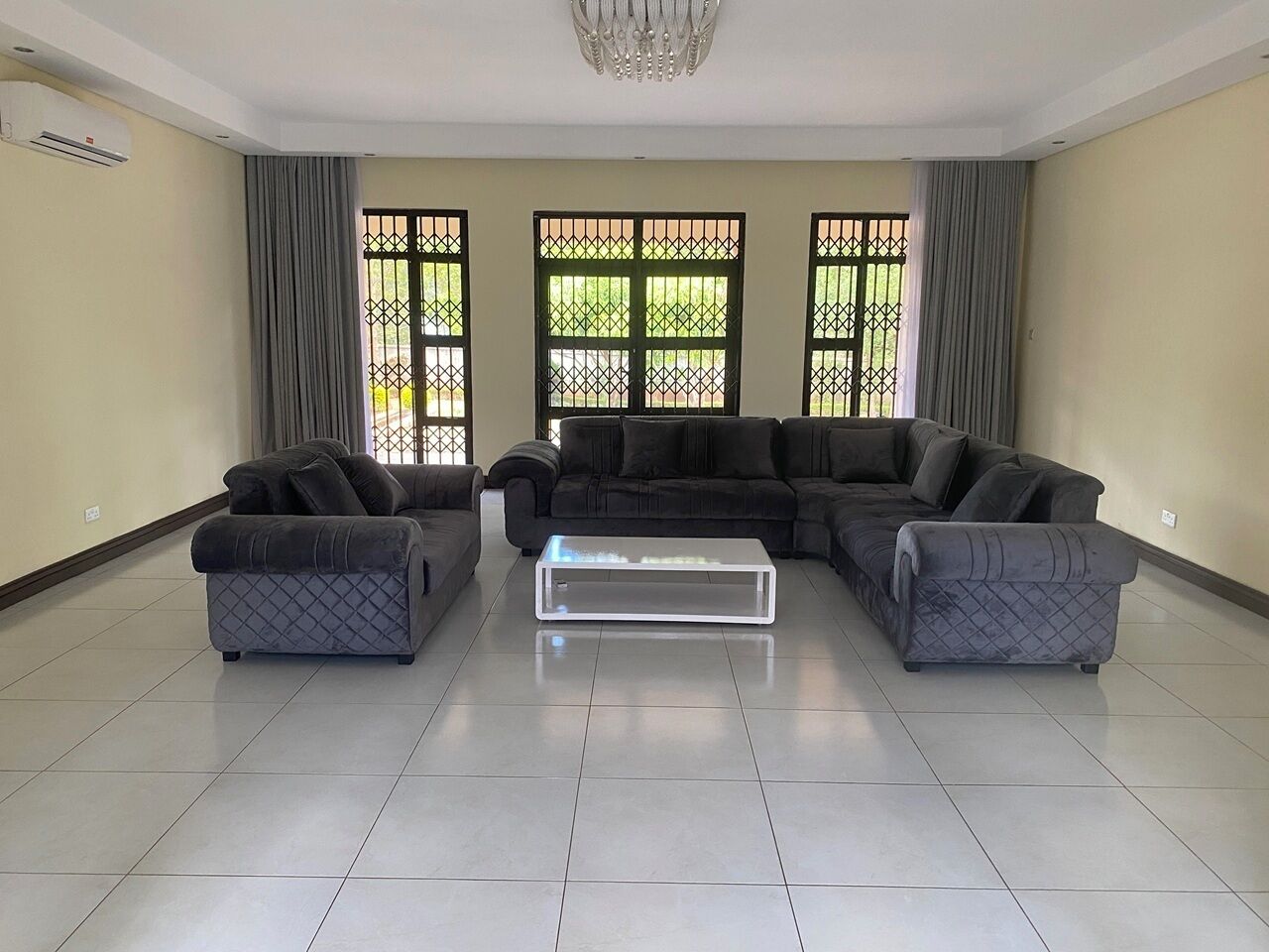 A living room with a sectional sofa, two armchairs, and a glass coffee table.