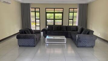 A living room with a sectional sofa, two armchairs, and a glass coffee table.