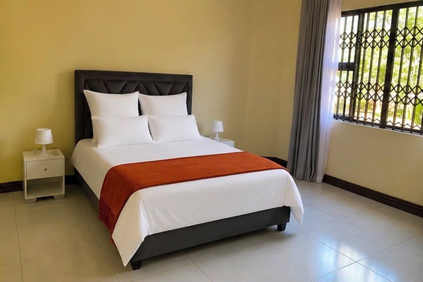 A hotel room with a bed, nightstands, and a window with a view.