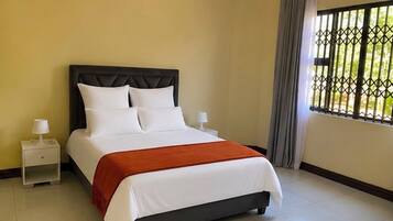 A hotel room with a bed, nightstands, and a window with a view.