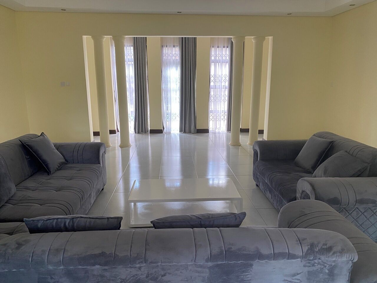 A living room with two sofas, a coffee table, and a view through a window with curtains.