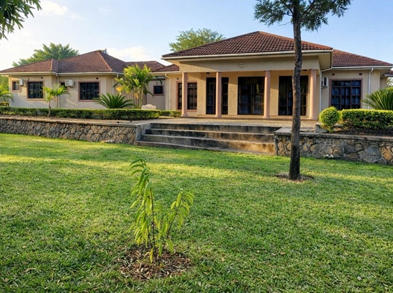 A residential house with a front lawn, a stone wall, and a clear sky.