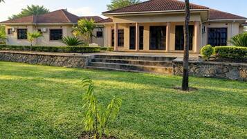 A residential house with a front lawn, a stone wall, and a clear sky.