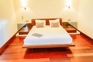 A hotel room with a wooden bed, two bedside lamps, and a bedside table. - Villa Las Palmeras - Five Bedroom Villa, Sleeps 10 (Puerto Calero)